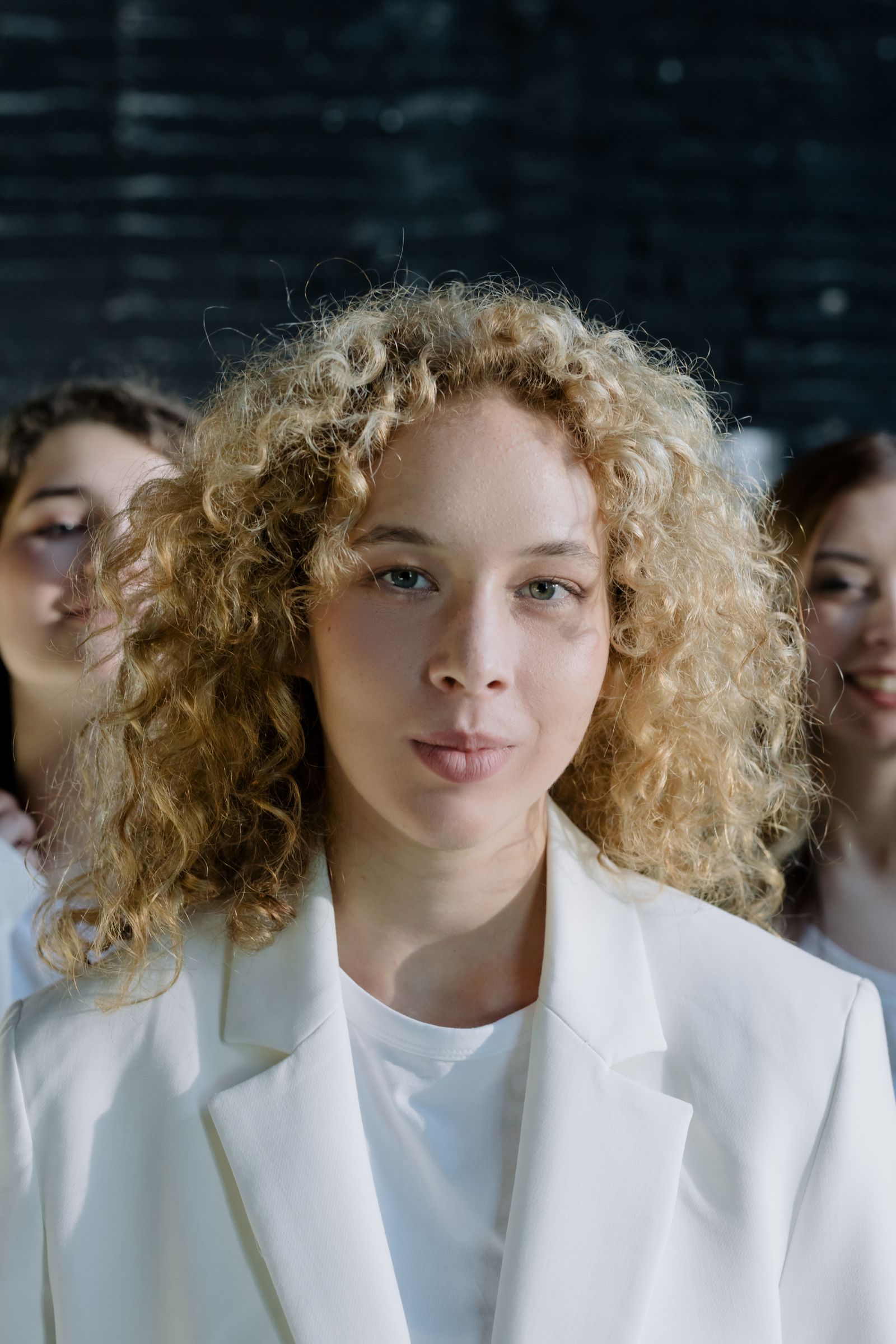 Trois personnes aux cheveux bouclés, la première au premier plan avec des boucles blondes définies