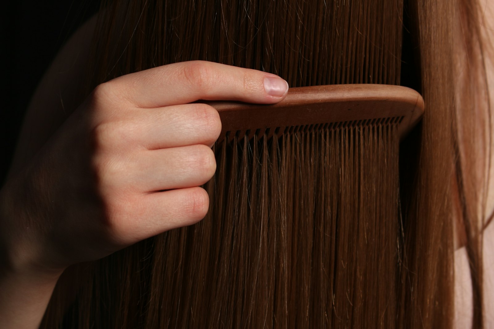 Une main peigne de longs cheveux bruns