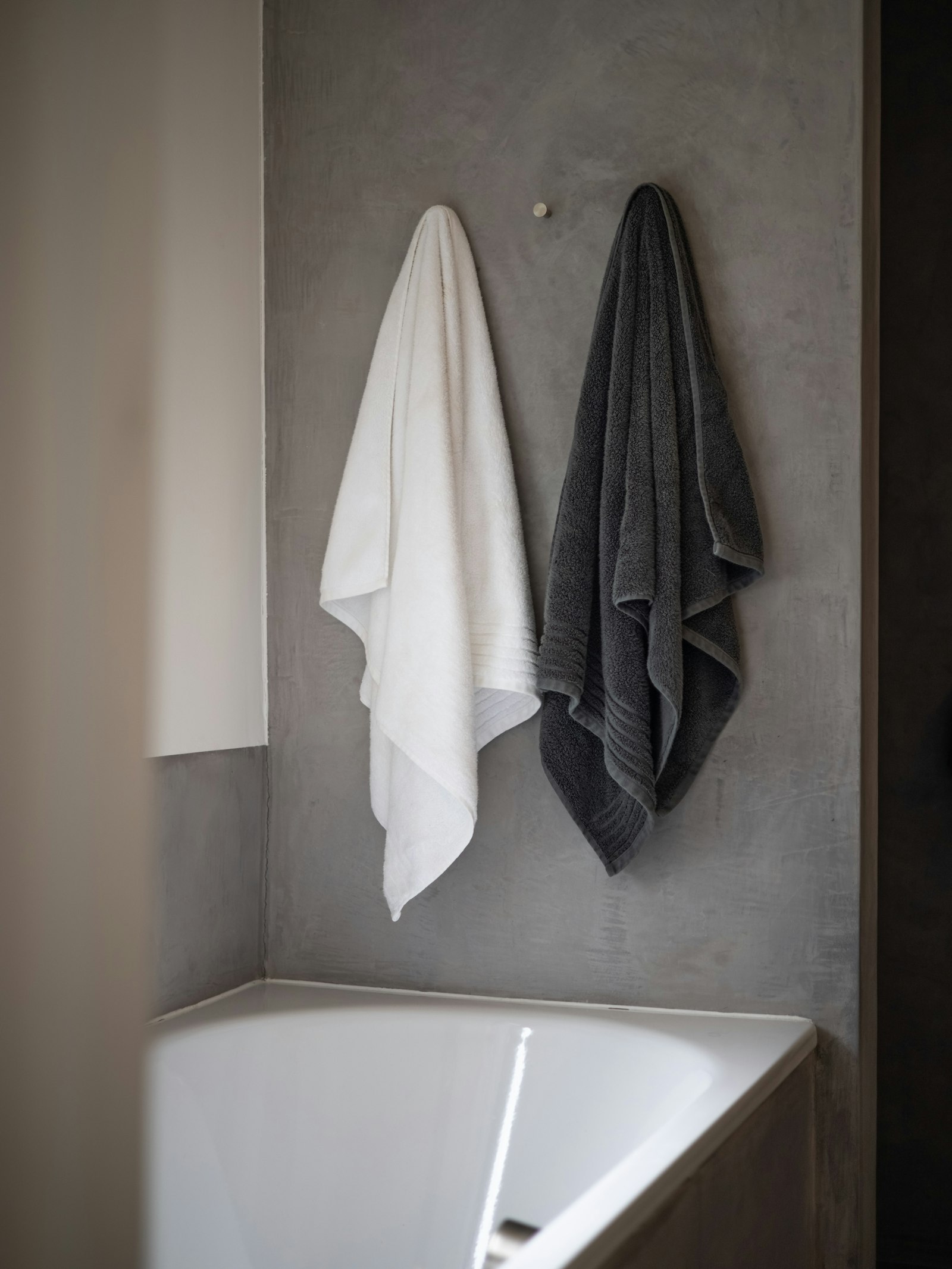 Serviette de bain blanche posée sur le rebord d’une baignoire en céramique