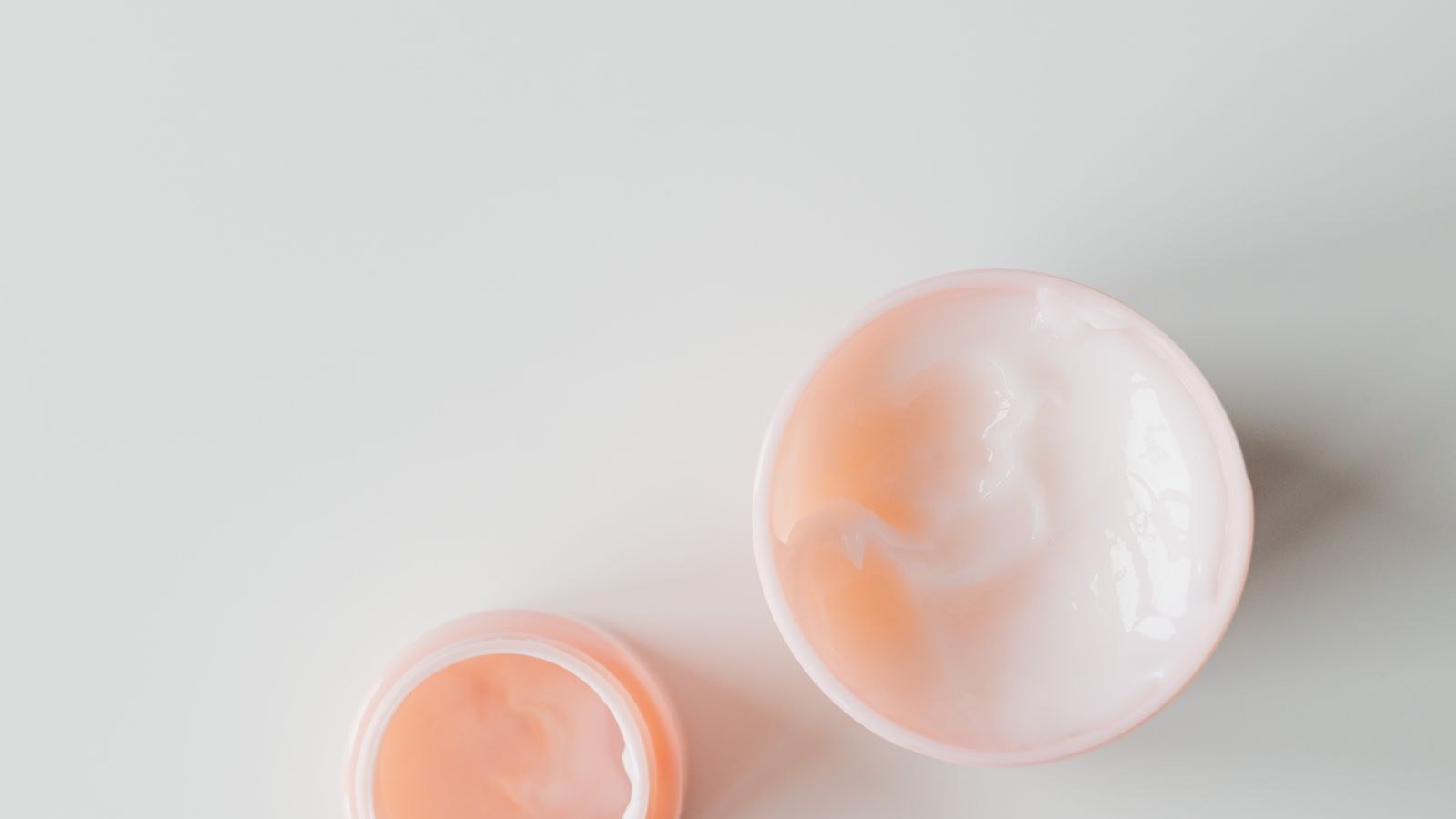 Deux pots de crème ouverts, vus de dessus sur un fond clair