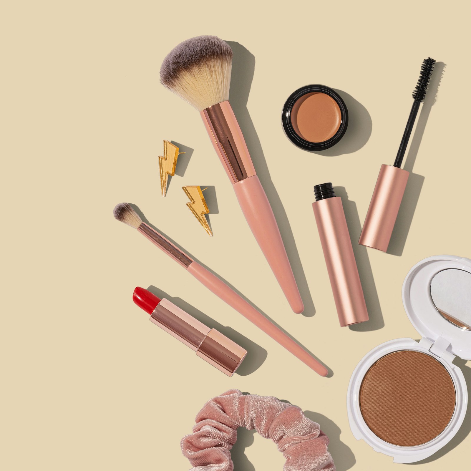 Pinceaux de maquillage et produits disposés sur un fond beige