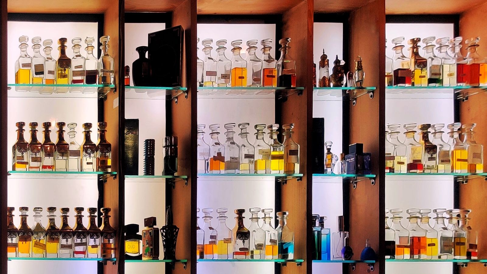 Rangées de flacons de parfum alignés sur les étagères éclairées d’une boutique spécialisée
