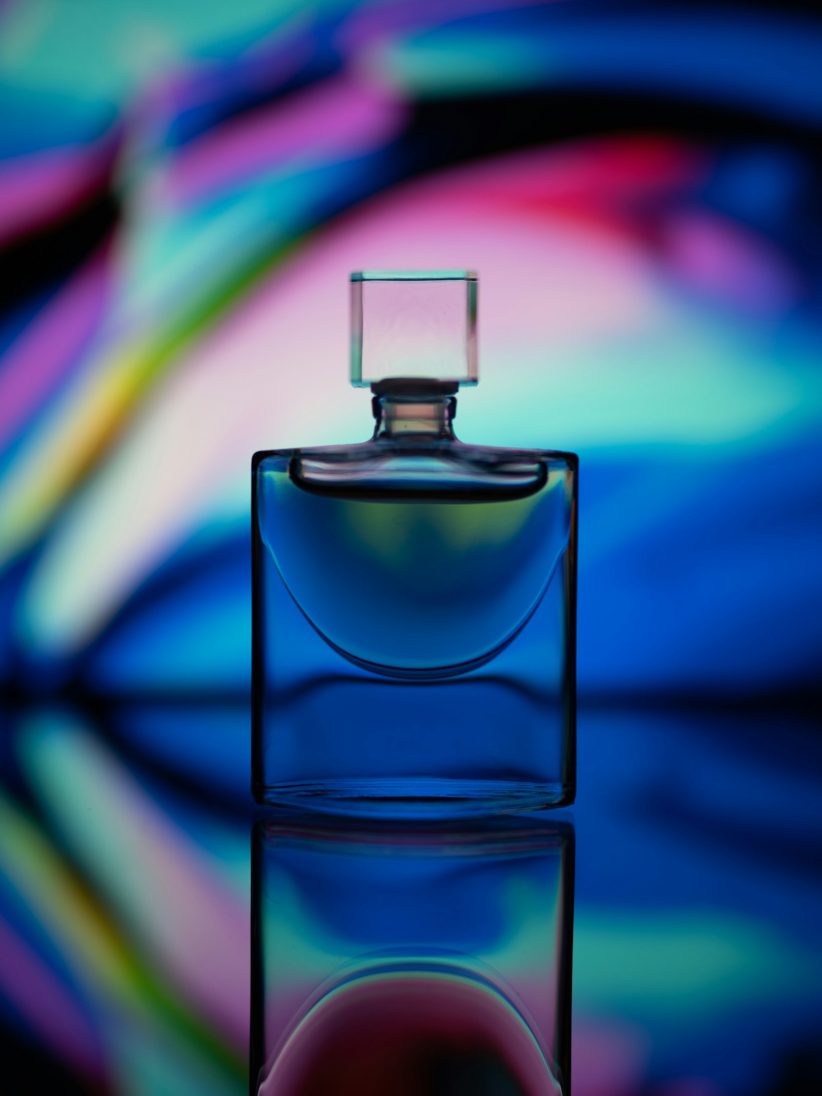 Flacon de parfum en verre éclairé par des lumières bleues et roses