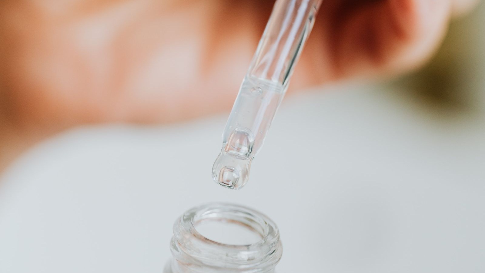 Une pipette de verre libère une goutte de sérum au-dessus d’un flacon dépoli