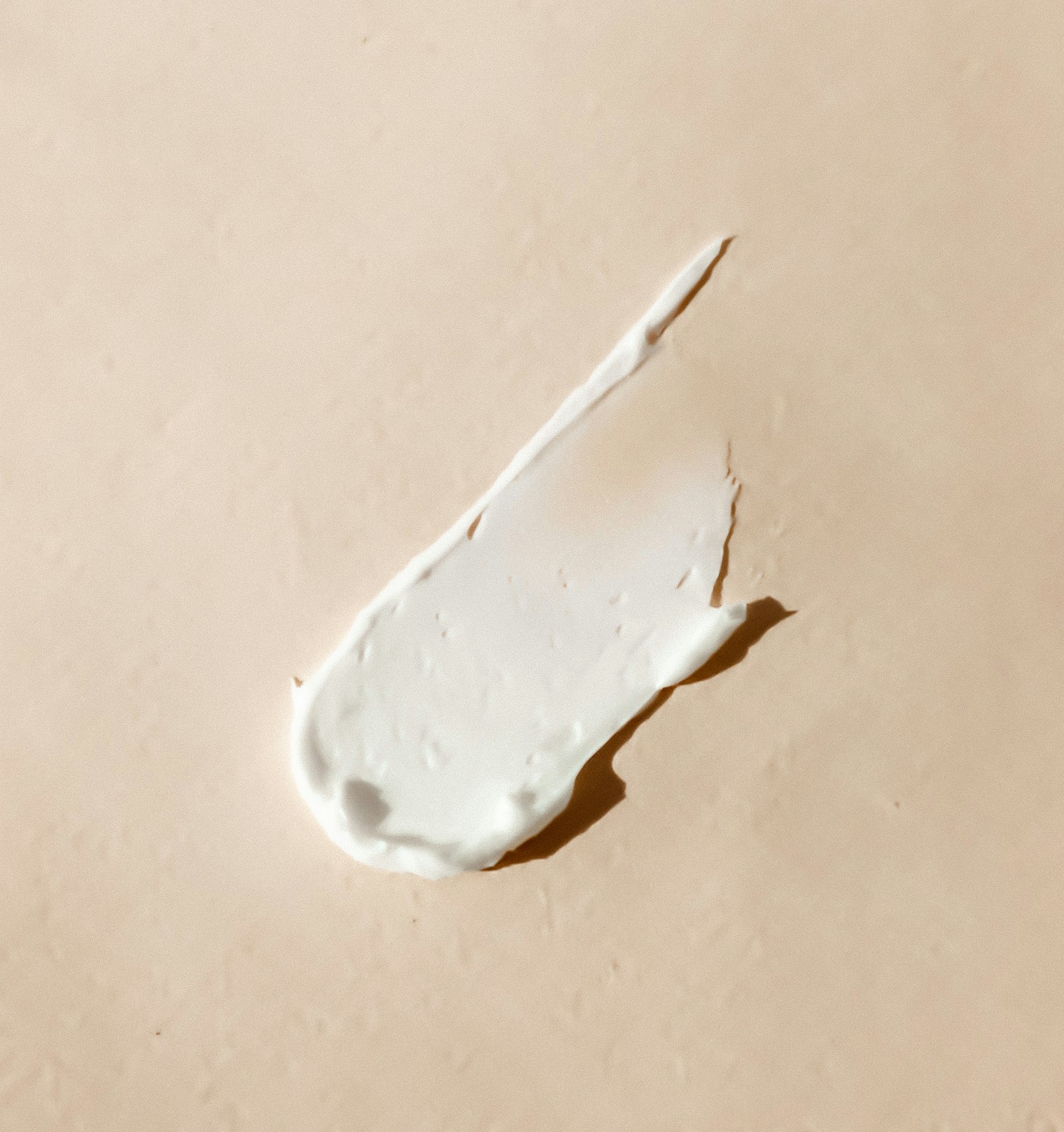Trace de crème blanche déposée sur un fond beige