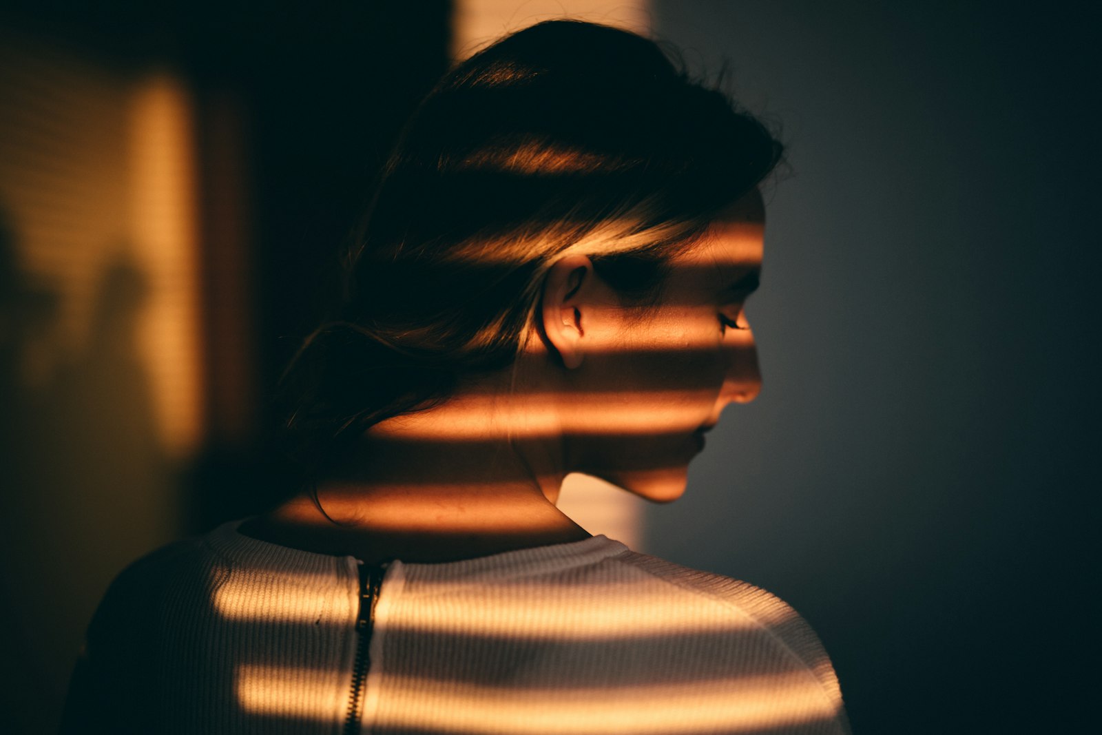 Visage traversé par la lumière du soleil filtrée par des stores